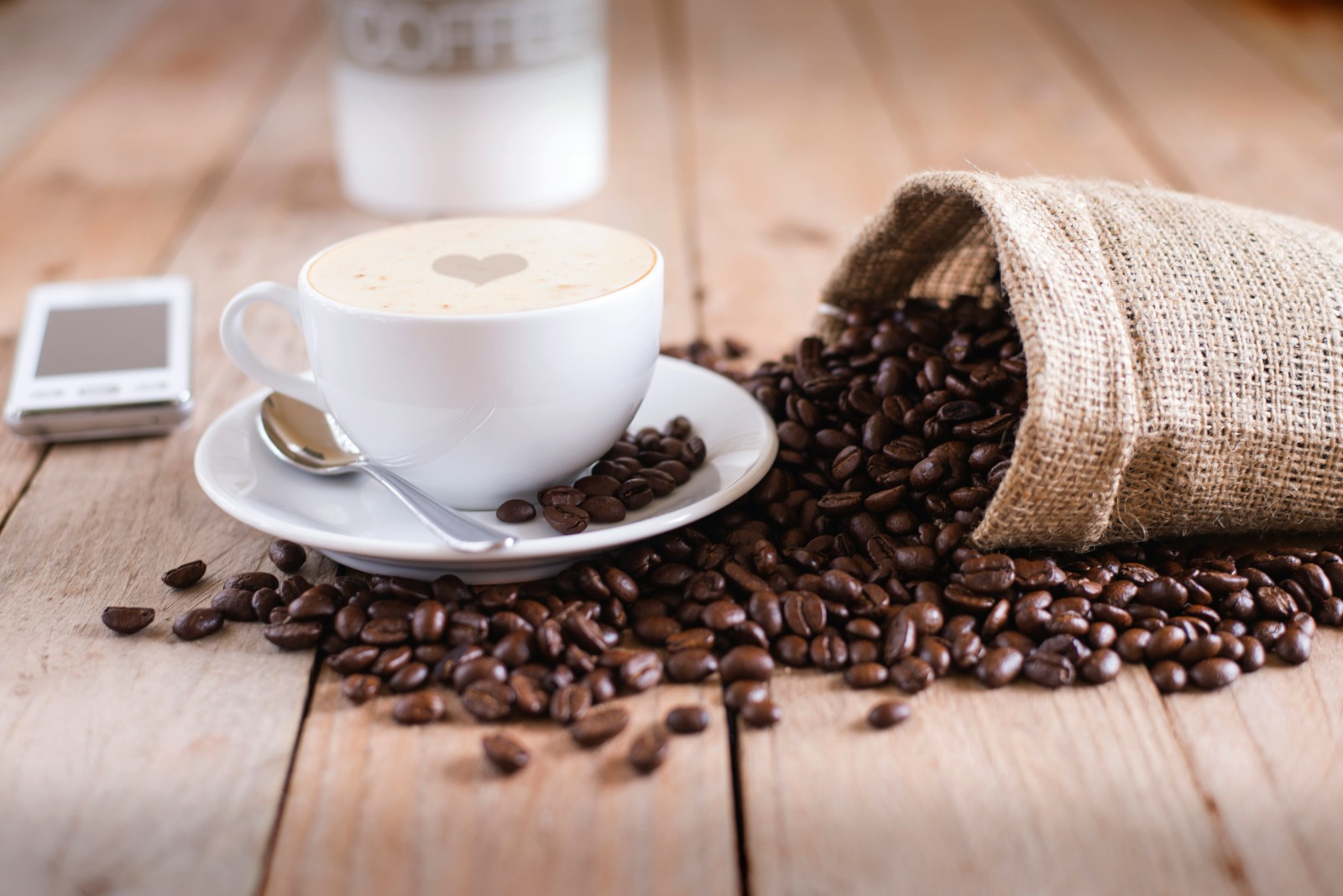 Xícara de café Ojuara ao lado de grãos torrados